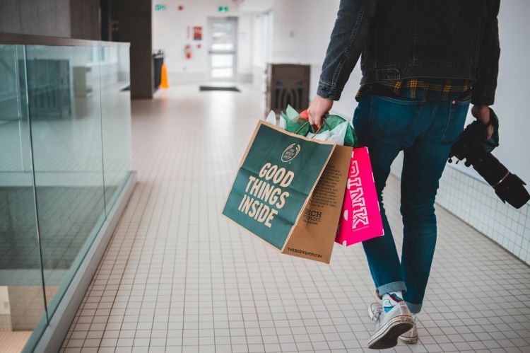 A man walking around a mall holding shopping bags.