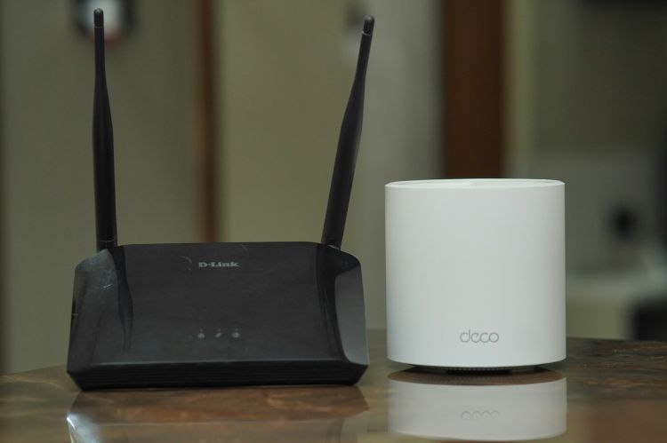 Closeup on a traditional wi-fi router and a mesh router sitting on a table.