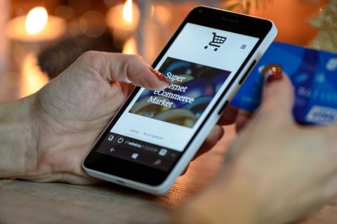 Woman with smartphone looking at shopping cart
