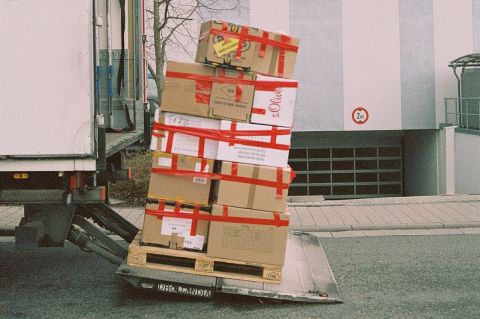 Shipping boxes piled behind a delivery truck.