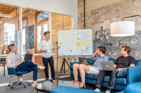 A man running a business meeting, pointing at a whiteboard