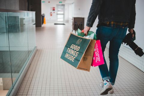 A man walking around a mall holding shopping bags.