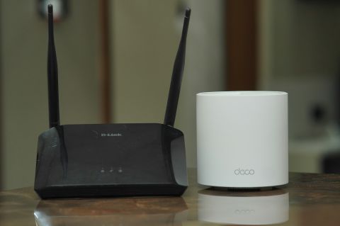 Closeup on a traditional wi-fi router and a mesh router sitting on a table.
