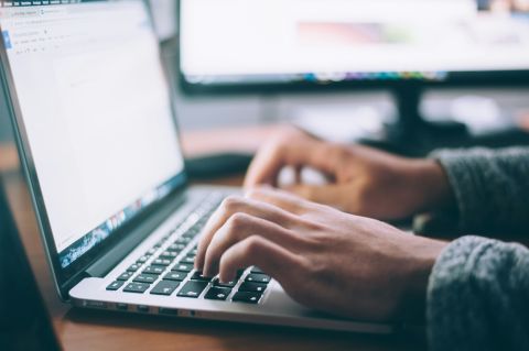 hands typing on a MacBook keyboard