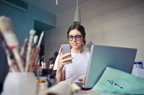 A woman holding a smartphone in an art studio