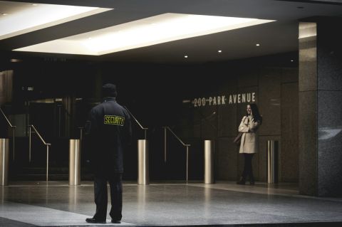 A security guard standing outside a building and watching the entrance